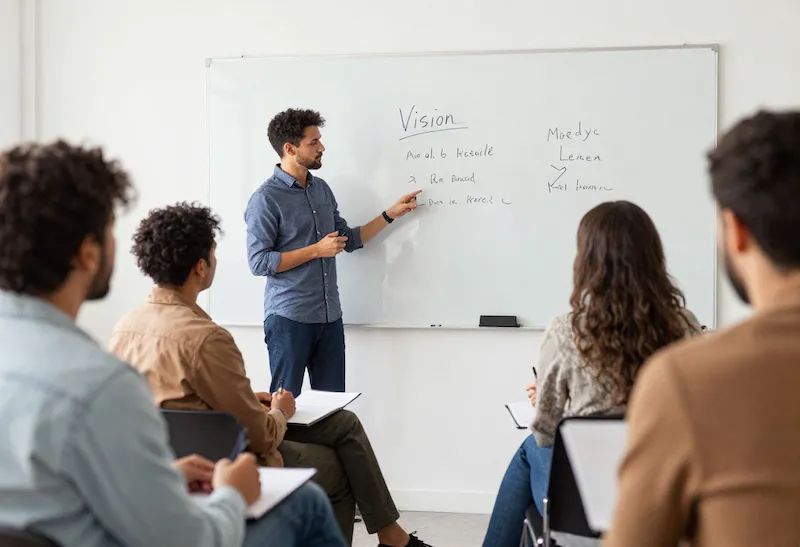 Man presenterar strategi vid whiteboard för grupp